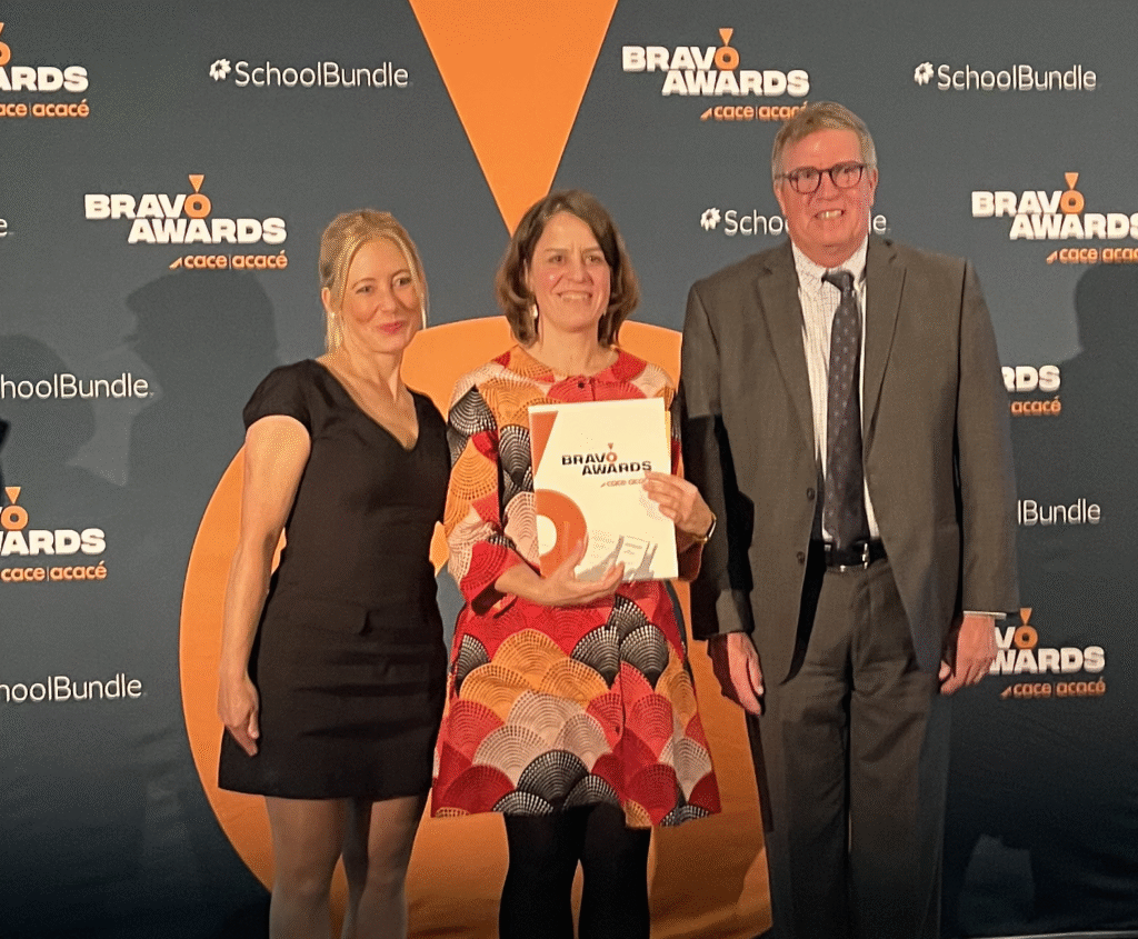 Trois personnes sur scène dont une reçoit un prix.